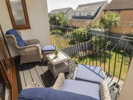 A balcony with wicker furniture and a garden view at Ty Traeth in Porthcawl