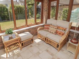 A conservatory with a sofa, table, chairs, and plants at Ty Traeth Porthcawl