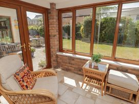 A conservatory with an armchair and a table at Ty Traeth in Porthcawl
