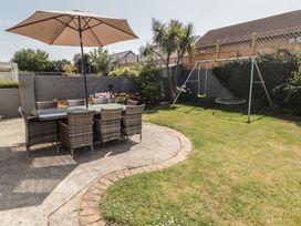 A garden with a dining set and swing set at Ty Traeth in Porthcawl