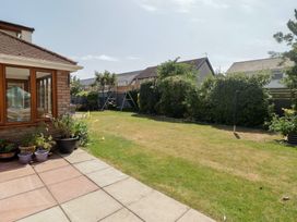 A garden with a swing and house at Ty Traeth in Porthcawl
