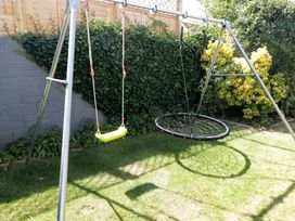 A swing set with a traditional swing and a nest swing in the garden at Ty Traeth in Porthcawl