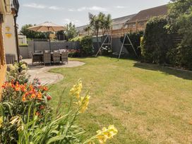 A garden with a table and chairs under an umbrella at Ty Traeth in Porthcawl