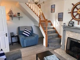 A living room with an armchair and staircase at 2 Bed Family Bungalow, WiFi, Parking, Garden, Dogs, Pentraeth