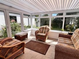 A conservatory with wicker furniture and windows at 2 Bed Family Bungalow, WiFi, Parking, Garden, Dogs in Pentraeth