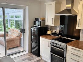 A kitchen with various appliances and a view into a sunroom at 2 Bed Family Bungalow, WiFi, Parking, Garden, Dogs, Pentraeth