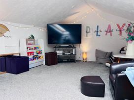 A snug with a television, shelf, and storage boxes at 2 Bed Family Bungalow, WiFi, Parking, Garden, Dogs, Pentraeth