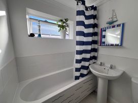 A bathroom with a bathtub, sink, and shower curtain at 2 Bed Family Bungalow, WiFi, Parking, Garden, Dogs in Pentraeth