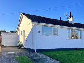 A bungalow with a garage and grassy area at 2 Bed Family Bungalow, WiFi, Parking, Garden, Dogs in Pentraeth