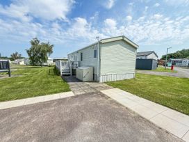 An outdoor area with a caravan and lawn at Super 2 bed 6 berth caravan pets go free in Hunstanton