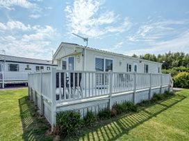 A caravan with a deck and grass area at Super 2 bed 6 berth caravan pets go free Hunstanton