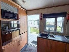 A kitchen with oven and microwave at Super 2 bed 6 berth caravan pets go free Hunstanton