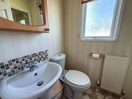 A bathroom with a sink, toilet, and mirror at Super 2 bed 6 berth caravan pets go free, Hunstanton