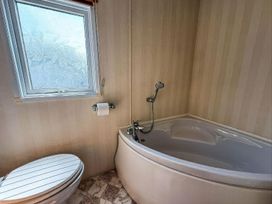 A bathroom with a bathtub and toilet at Super 2 bed 6 berth caravan pets go free Hunstanton