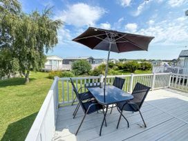 An outdoor patio with a table and chairs under an umbrella at Super 2 bed 6 berth caravan pets go free Hunstanton