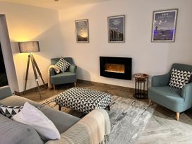 A living room with a sofa, armchairs, ottoman, and fireplace at The Old Barn in Manchester