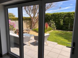 A garden view with chairs and a table through glass doors at The Old Barn in 