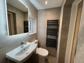 A bathroom with a sink, toilet, mirror, and towel rail at The Old Barn in Manchester
