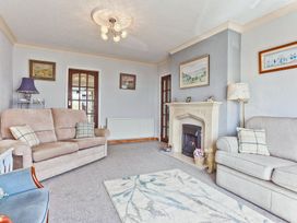 A living room with a sofa, armchair, fireplace, and wall art at Lothlorien in Grange over Sands