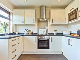 A kitchen with cabinets, oven, sink, and countertop at Lothlorien in Grange over Sands