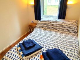 A bedroom with a bed and towels on top at Painters Cottage 2Bed Chalet Free Leisure Passes Near St Ives