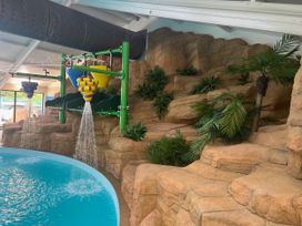 An indoor pool area with a water slide and rock formation at Painters Cottage 2Bed Chalet Free Leisure Passes Near St Ives