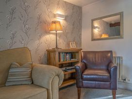 A living room with a sofa, armchair, and bookshelf at Cosy cottage near scenic walks and country pub, Penrith