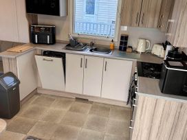 A kitchen with appliances and cabinets at R&R Coastal Retreats Cedars 63 in Skegness
