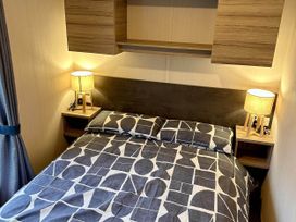 A bedroom with a bed and lamps at R&R Coastal Retreats Cedars 63 in Skegness