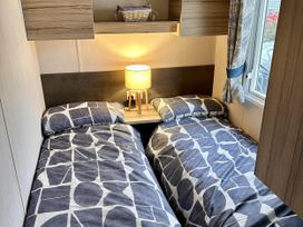 A bedroom with two single beds and a lamp at R&R Coastal Retreats Cedars 63 in Skegness