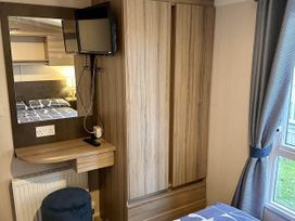 A bedroom with a wardrobe and television at R&R Coastal Retreats Cedars 63, Skegness