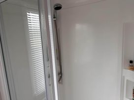 A bathroom with a shower and a bottle on a shelf at R&R Coastal Retreats Cedars 63 Skegness