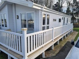 An outdoor view of a lodge with a wooden deck at Cayton Bay Lodge Parkdean Resorts Scarborough