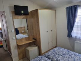 A bedroom with a wardrobe and bed at Cayton Bay Lodge Parkdean Resorts in Scarborough