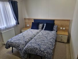 A bedroom with two beds and a bedside table at Cayton Bay Lodge Parkdean Resorts in Scarborough