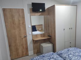 A bedroom with a bed, TV, and wardrobe at Cayton Bay Lodge Parkdean Resorts, Scarborough