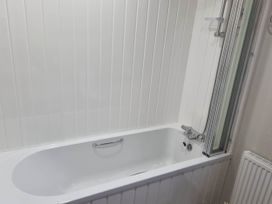A bathroom with a bathtub and shower screen at Cayton Bay Lodge Parkdean Resorts Scarborough