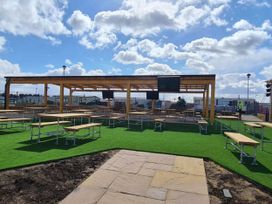 An outdoor area with tables and benches under a canopy at Cayton Bay Lodge Parkdean Resorts, Scarborough