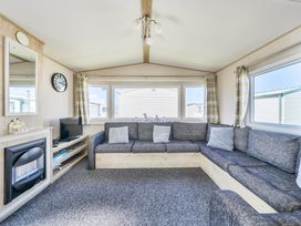 A living room with a sofa and television at Sleeps 8 Communal Spa Access Parking Rhyl