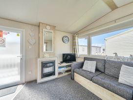A living room with a sofa and television at Sleeps 8 Communal Spa Access Parking in Rhyl