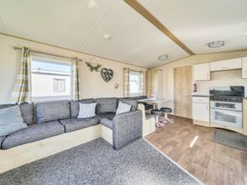 A living room with a sofa and kitchen unit at Sleeps 8 Communal Spa Access Parking Rhyl