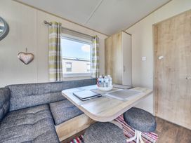 A dining area with a table and sofa at Sleeps 8 Communal Spa Access Parking in Rhyl