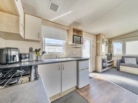 A kitchen with appliances and seating area at Sleeps 8 Communal Spa Access Parking Rhyl