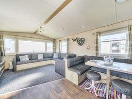 A living room with a sofa and dining area at Sleeps 8 Communal Spa Access Parking Rhyl