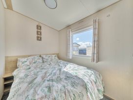 A bedroom with a bed and window at Sleeps 8 Communal Spa Access Parking Rhyl