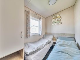 A bedroom with two beds and a window at Sleeps 8 Communal Spa Access Parking Rhyl