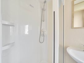 A shower with a sink and mirror in the bathroom at Sleeps 8 Communal Spa Access Parking Rhyl