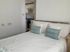 A bedroom with a bed and pillows visible towards a kitchen at Bungalow Sleeps 2 Parking in Newquay