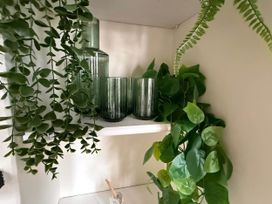 A shelf with green glass vases and drinking glasses along with artificial plants at Cotswolds Castle Sleeps 8 with Enclosed Garden in Banbury