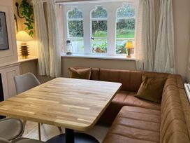 A dining room with a wooden table and sofa at Cotswolds Castle Sleeps 8 with Enclosed Garden, Banbury